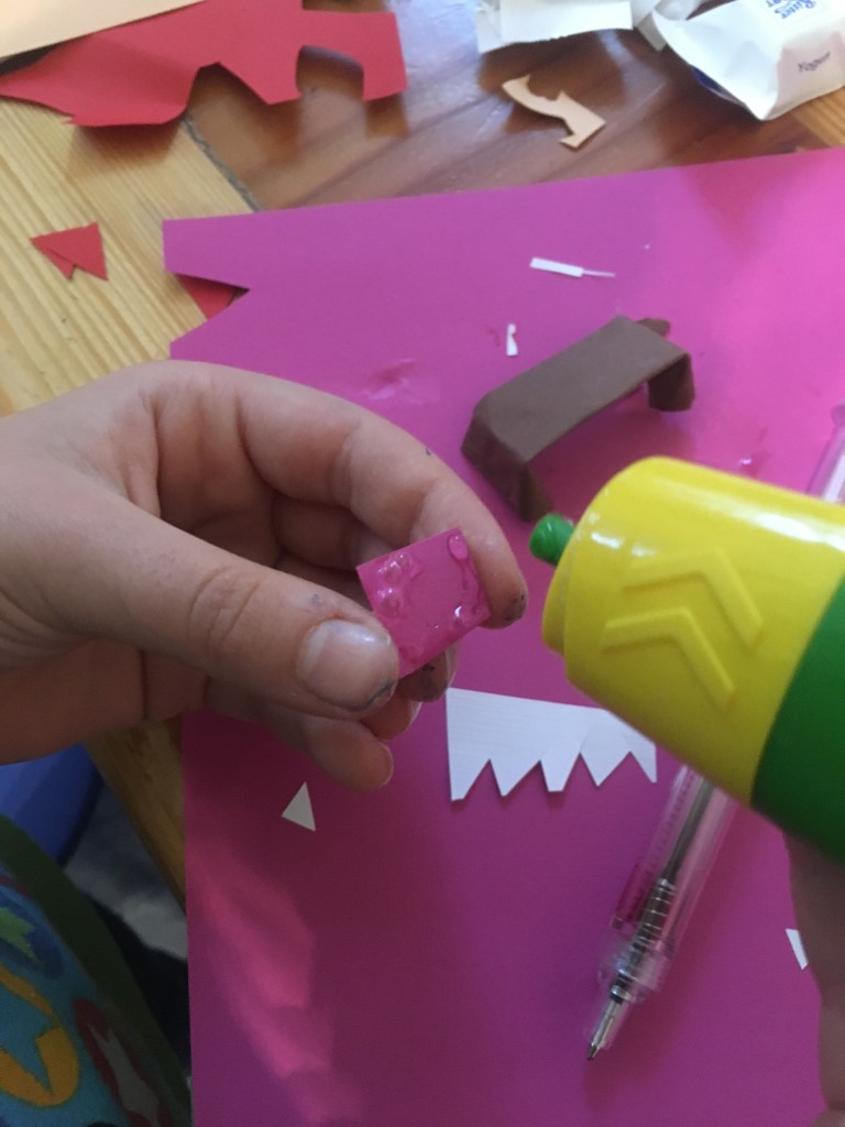 Kind trägt Kleber auf Papier auf