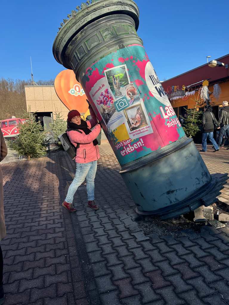 Frau hält kippende Litfaßsäule