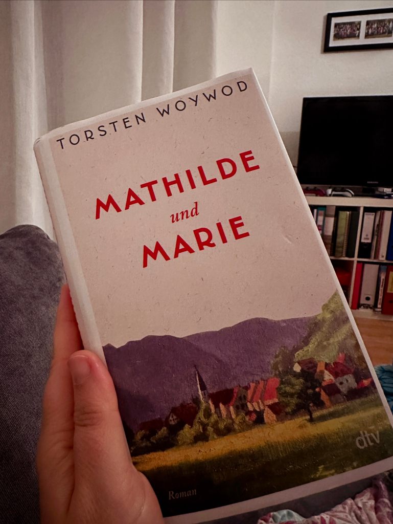 Buch mit dem Titel "Mathilde und Marie" und einem kleinen Dorf vor Bergen auf dem Titel