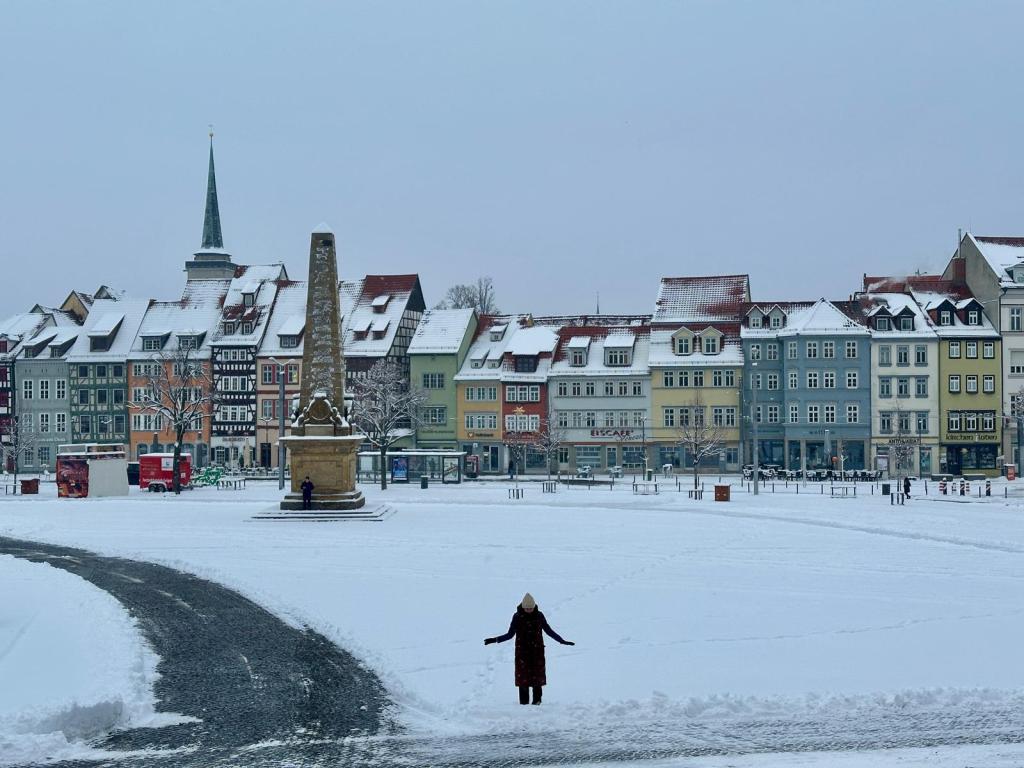 Bunte Häuser und eine Gedenksäule in der Mitte eines Platzes