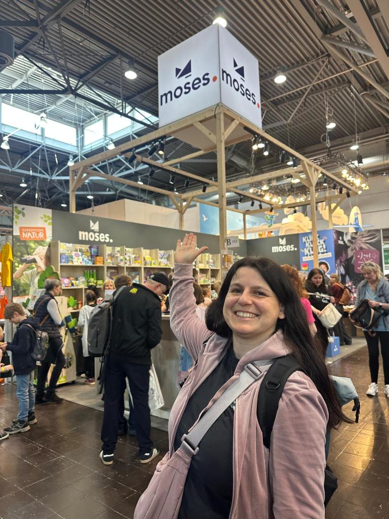 Frau auf Messe zeigt auf ein Schild, auf dem "moses" steht