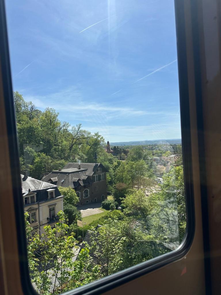 Blick aus einem Bahnfestner auf Gebäude am Hang