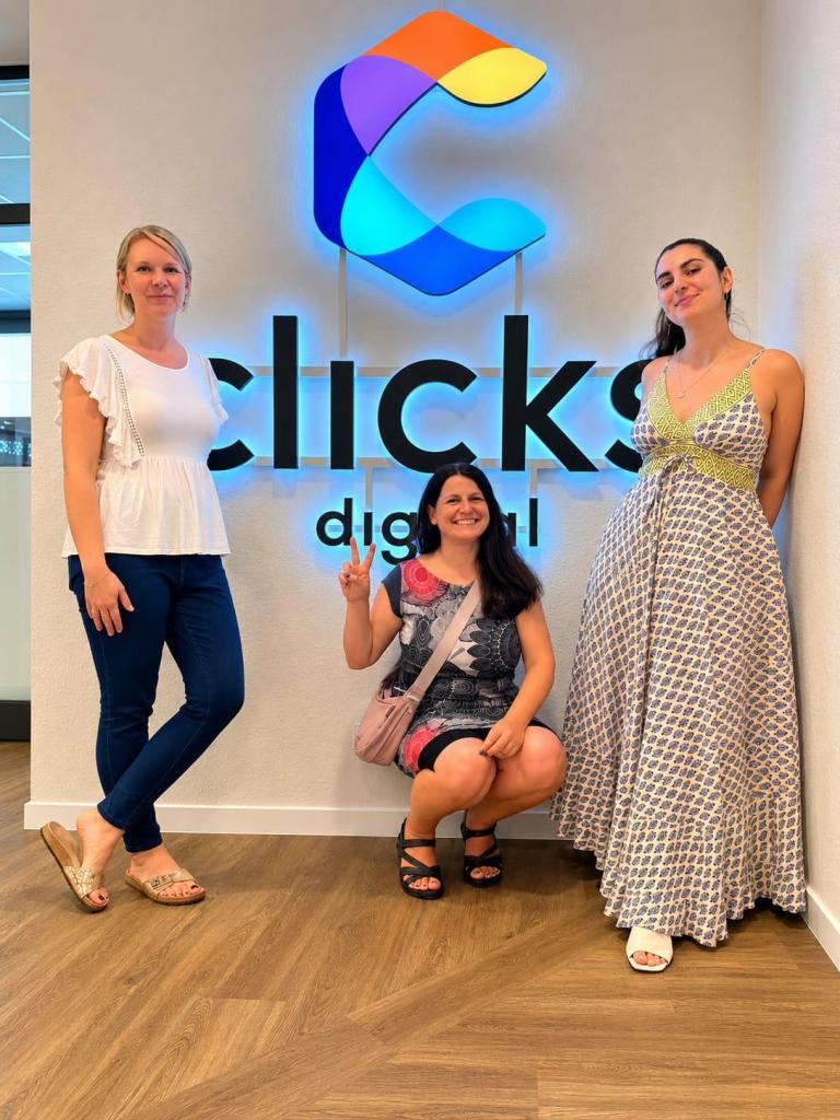 Drei Frauen an einer Wand mit Logo clicks digital
