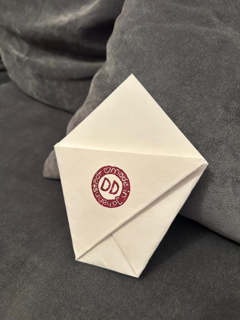 Zu einer kleinen Tüte gefaltetes Papier und Stempel: made in Johannstadt